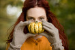 A young woman holding a small pumpkin