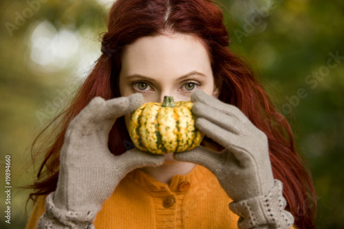 Foto: A young woman holding a small pumpkin A young woman holding a small pumpkin