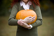 A young woman holding a pumpkin
