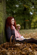A young woman sitting beneath a tree, eating bread and cheese