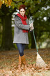 A young woman standing with a rake in autumn time