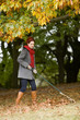 A young woman raking up autumn leaves