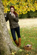 A young woman standing next to a tree, eating chocolate