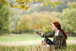 A young woman sitting in the grass, looking at a leaf