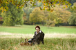 A young woman sitting in the grass with a wicker basket