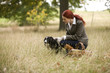 A young woman in a field stroking her dog