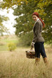 A young woman standing in a field, holding a wicker basket