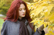A young woman looking at autumn leaves