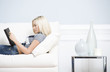 Young Woman Lying on Sofa Reading Book