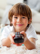 Smiling little boy watching TV lying on the floor Smiling little boy watching TV lying on the floor