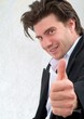 Ein junger Mann lacht und zeigt Daumen hoch. Sample Text.