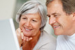 Closeup of a smiling elderly couple using a laptop together