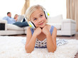 Adorable little girl listening music lying on the floor