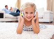 Happy little girl listening music lying on the floor