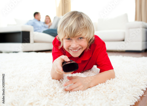 Happy boy holding a remote lying on the floor Happy boy holding a remote lying on the floor
