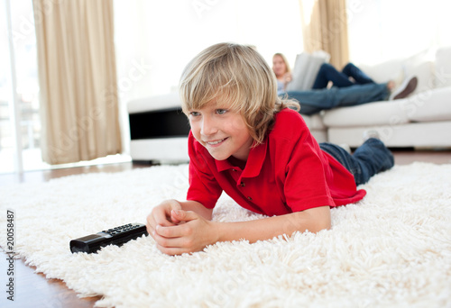 Concentrated boy watching TV lying on the floor