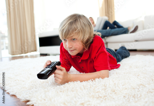 Cute boy holding a remote lying on the floor Cute boy holding a remote lying on the floor