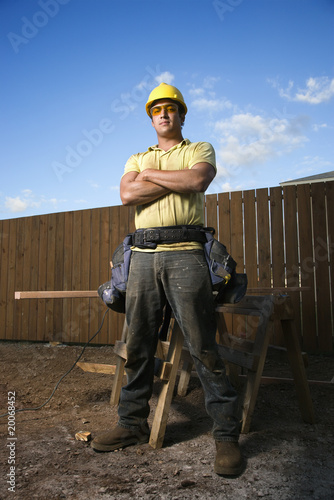Photo: Male Construction Worker Stands with Folded Arms Male Construction Worker Stands with Folded Arms