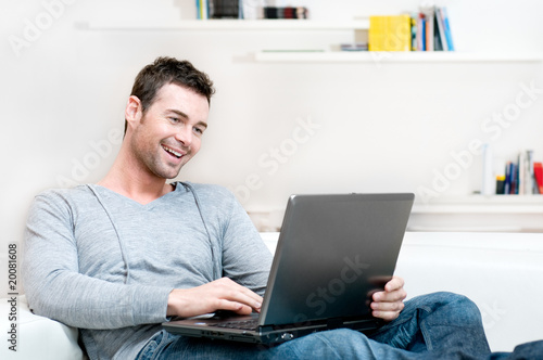 Photo: Smiling young man working on laptop Smiling young man working on laptop