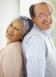 Smiling mature couple standing back to back
