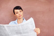 Pretty young woman reading newspaper with copyspace
