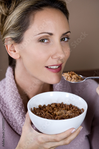 Photo: A mid adult woman eating a bowl of chocolate coated cereal A mid adult woman eating a bowl of chocolate coated cereal