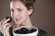 A mid adult woman eating a plum