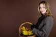 A woman holding a basket of conkers, acorns and autumn leaves