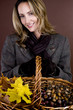A woman holding a basket of conkers, acorns and autumn leaves