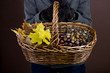 A woman holding a basket of conkers, acorns and autumn leaves