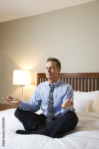 Photo: Businessman Meditating on Bed Businessman Meditating on Bed