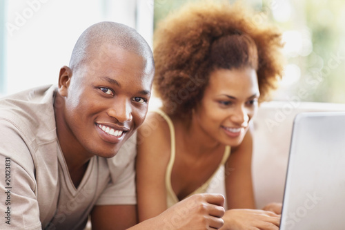 Foto: Happy young couple on the couch with a laptop Happy young couple on the couch with a laptop