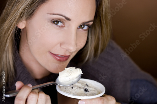 Photo: A mid adult woman eating ice cream, close-up A mid adult woman eating ice cream, close-up