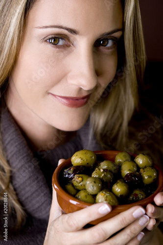 Photo: A mid adult woman holding a dish of mixed olives A mid adult woman holding a dish of mixed olives