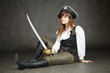 Woman - captain of pirates sitting on black background with a sa