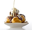 profiteroles with hot chocolate and cream on white plate profiteroles with hot chocolate and cream on white plate
