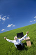Businessman Celebrating Arms Raised At Desk In Green Field