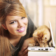girl smiling next to kitten on laptop