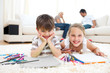 Smiling siblings drawing lying on the floor