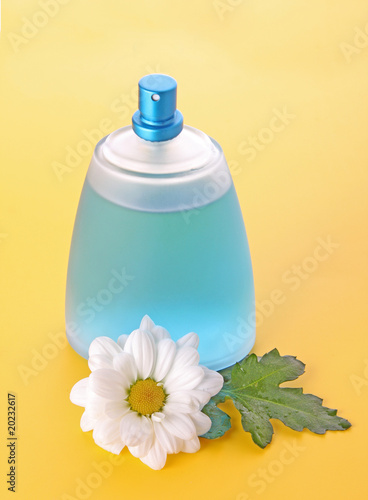 Photo: Bottle of perfume and camomile on yellow background Bottle of perfume and camomile on yellow background