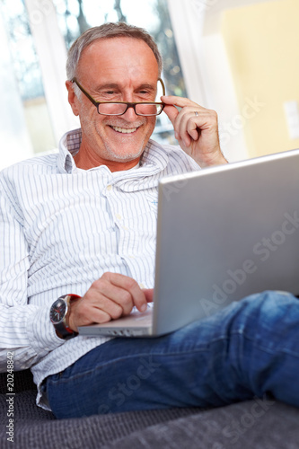 Photo: Mature man with laptop and reading specs Mature man with laptop and reading specs