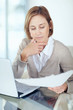 Photo: Mature businesswoman reading the documents in office Mature businesswoman reading the documents in office