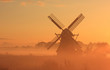 Dutch windmill in autumn fog during sunrise.