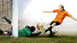 Shoot of football player and jump of goalkeeper on the field of