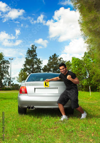 Photo: Happy male driver holding learner licence plates beside car Happy male driver holding learner licence plates beside car