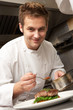 Chef Adding Sauce To Dish In Restaurant Kitchen