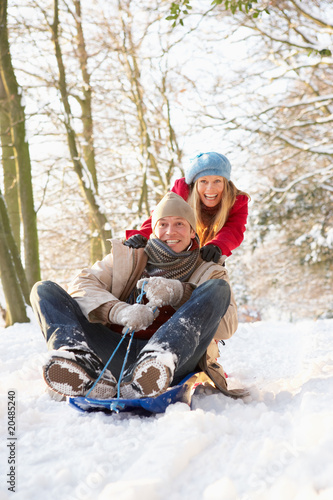 Photo: Couple Sledging Through Snowy Woodland Couple Sledging Through Snowy Woodland
