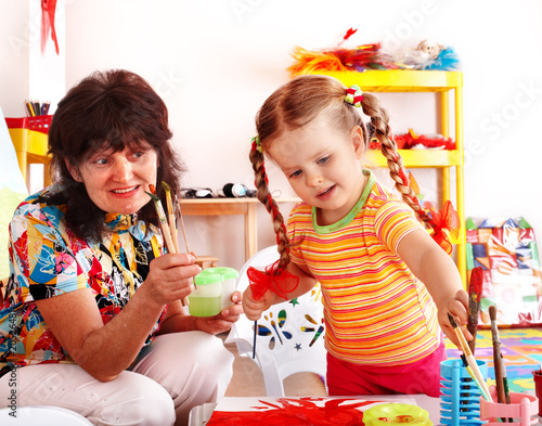 Photo: Child with teacher draw paints in playroom. Child with teacher draw paints in playroom.