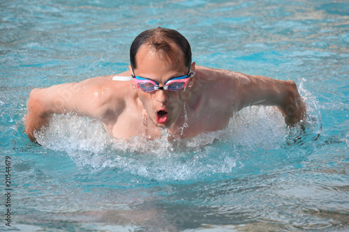 Photo: man in watersport goggles swimming in pool, jumped out of water man in watersport goggles swimming in pool, jumped out of water