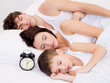 amily sleeping with alarm clock near  their  heads